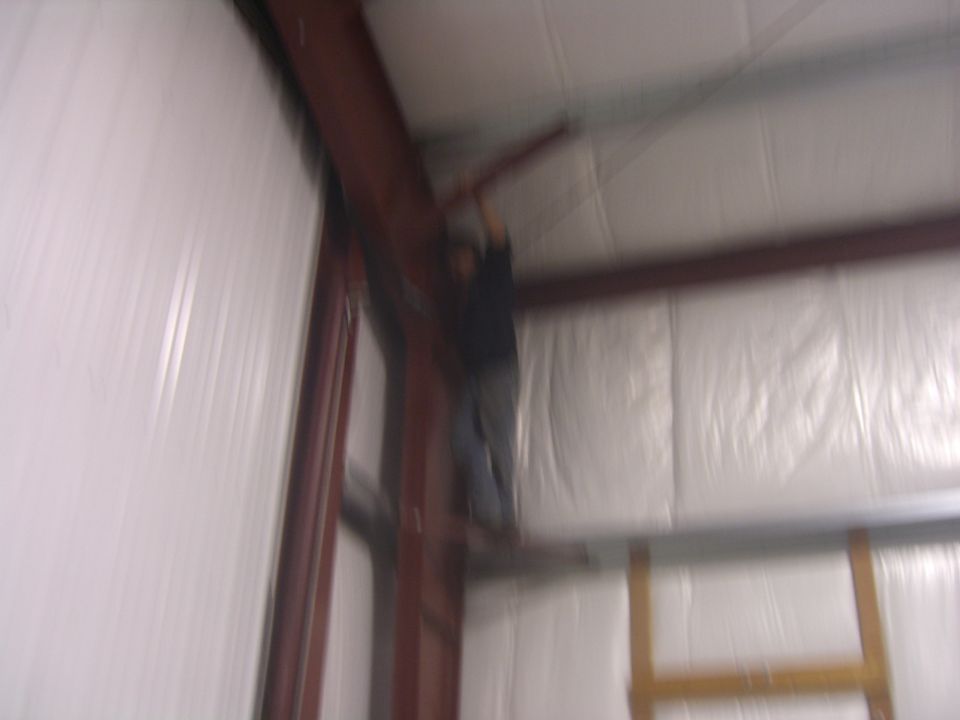 Person working on metal beams inside a building with white insulated walls. Supermotors.net logo visible