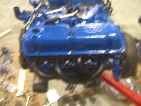 1979 Ford Bronco - A blue Ford engine is shown with various tools scattered around it on a workbench.