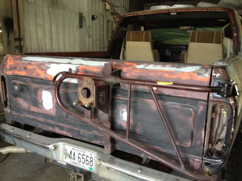 1979 Ford Bronco - The rear of a 1978 Ford Bronco is visible, with its tailgate and bumper showing signs of rust and repair work.
