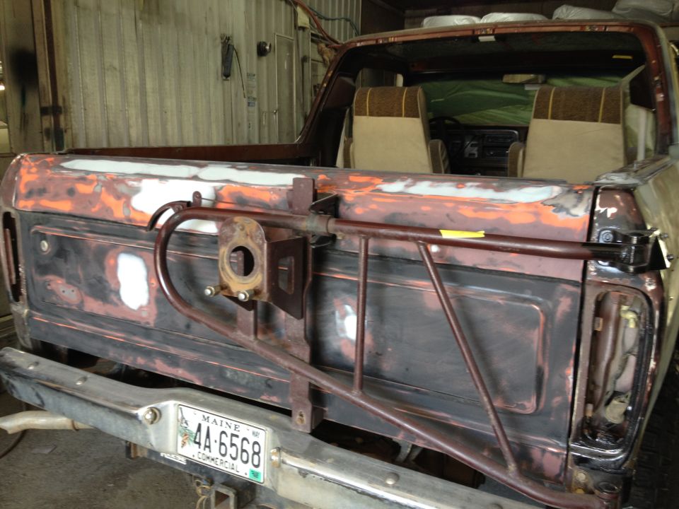 Rear of a 1978 Ford Bronco undergoing restoration, showing a rusty tailgate and bumper