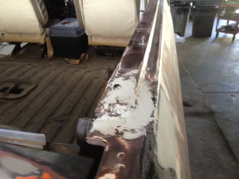 1979 Ford Bronco - The interior of a vehicle shows tan seats and a metal floor with visible rust and peeling paint on a body panel.