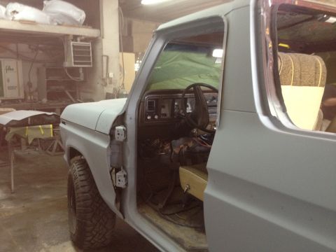 1979 Ford Bronco - Side view of a 1978 Ford Bronco in a workshop, with the door open revealing the interior.