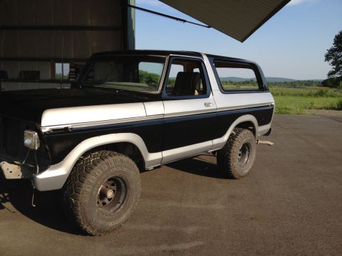 1979 Ford Bronco - This two-tone black and silver Ford Bronco is parked in a garage with the door open.