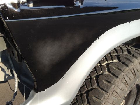 1979 Ford Bronco - Close-up of a black fender flare and tire on a vehicle, with a silver body panel visible below.