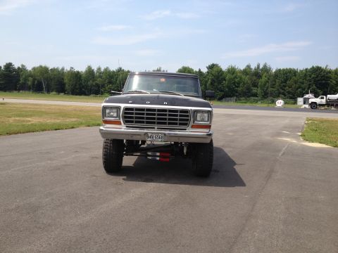1979 Ford Bronco - This lifted Ford truck, possibly a 1979 model, is parked on asphalt with trees in the background.