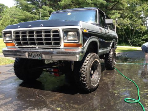1979 Ford Bronco - A lifted 1979 Ford Bronco is shown from the front, with a black hood and silver and black body.