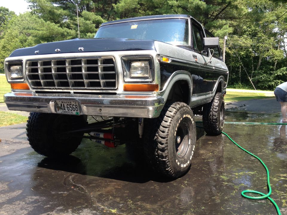 Black and silver 1979 Ford Bronco with lifted suspension and off-road tires, viewed from the front