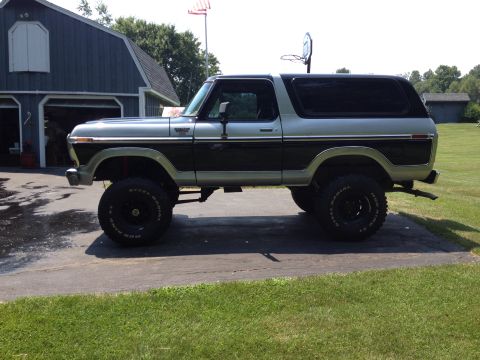 1979 Ford Bronco - This lifted two-tone Bronco features prominent black trim and oversized tires, viewed from the side.