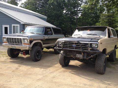 1979 Ford Bronco - Two Ford Broncos, a gray two-tone and a tan model, are parked outdoors on a dirt lot.