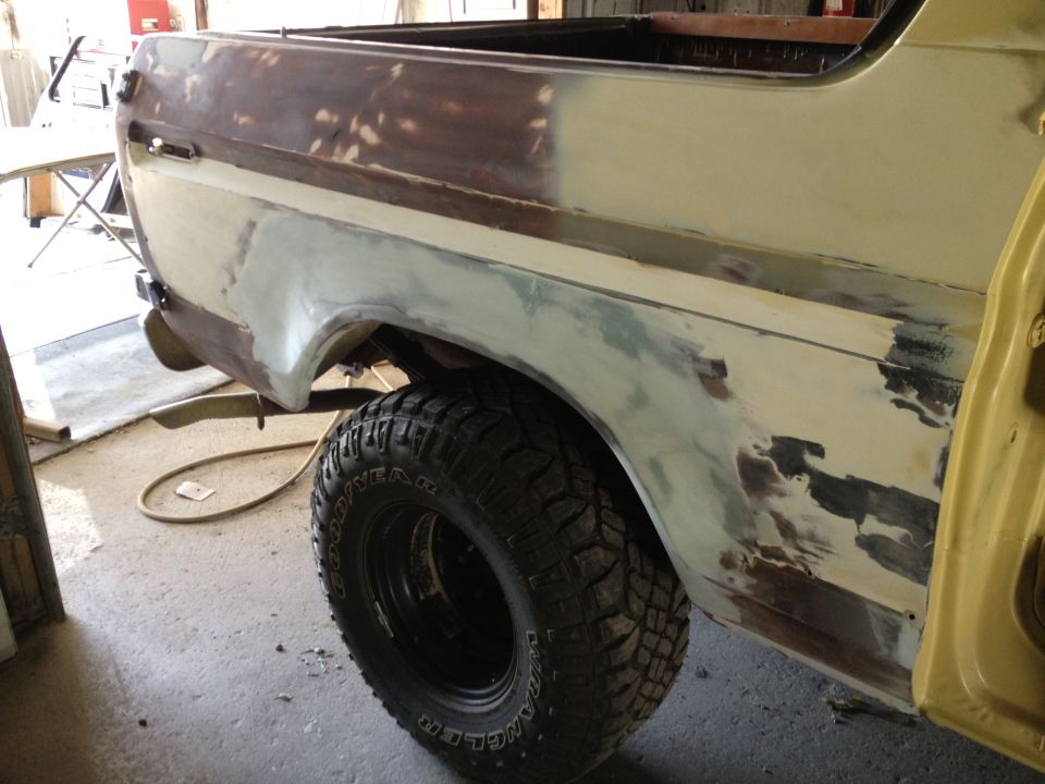 Rear quarter panel of a Ford Bronco undergoing bodywork, showing primer and body filler