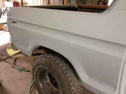 1979 Ford Bronco - Close-up of a primed rear quarter panel and tire on a Ford Bronco, likely undergoing restoration.
