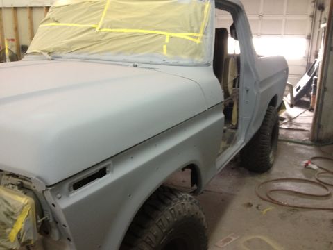 1979 Ford Bronco - A gray Ford Bronco is in a garage, with its doors open and windows taped for painting.