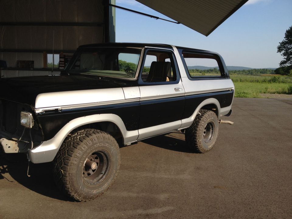 Two-tone black and silver Ford Bronco with off-road tires parked in a garage