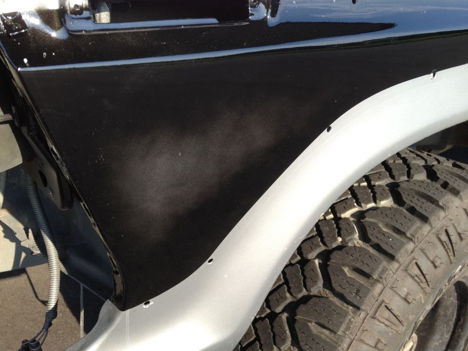 Black fender flare over silver body panel and tire
