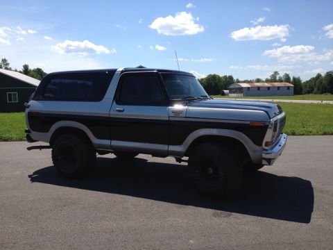 1979 Ford Bronco - Side view of a two-tone 1979 Ford Bronco under a partly cloudy sky.