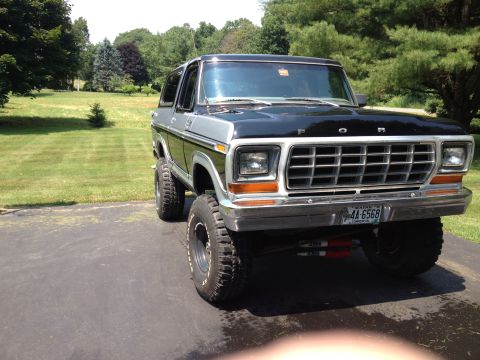 1979 Ford Bronco - This lifted Ford Bronco is parked on a paved surface with a grassy lawn in the background.
