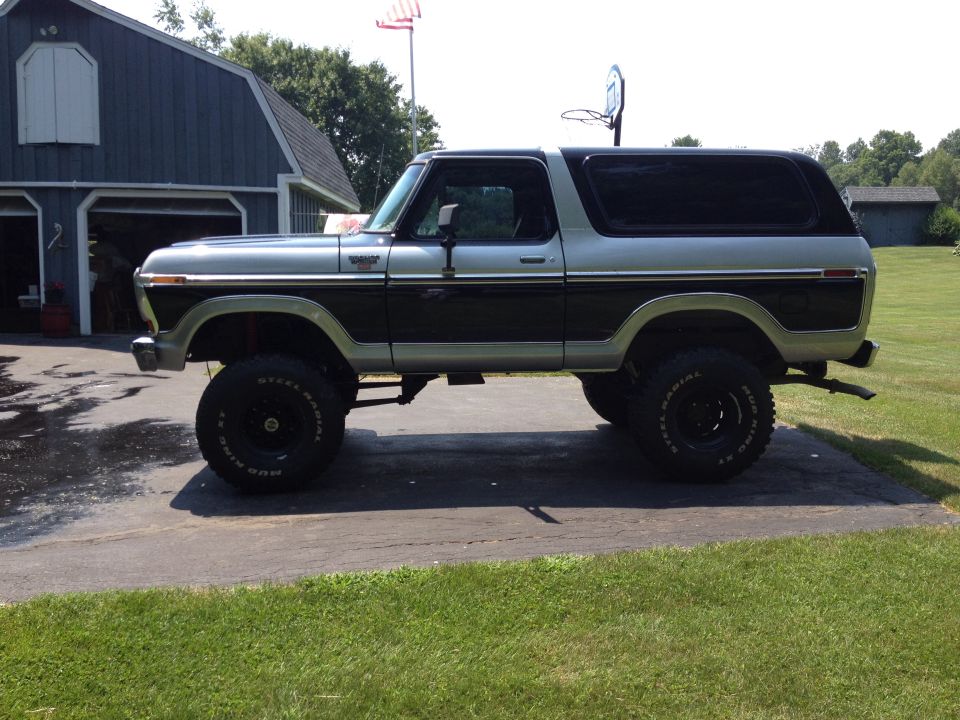 Lifted two-tone SUV with black trim and large tires, parked in driveway