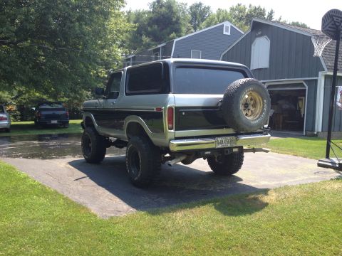 1979 Ford Bronco - Rear view of a lifted 1979 Ford Bronco with a spare tire on the tailgate, parked in a driveway.