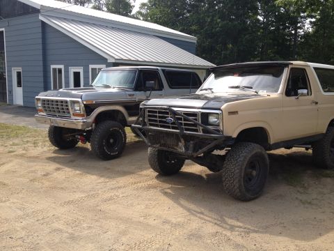 1979 Ford Bronco - Two Ford Broncos are parked side-by-side in front of a building.