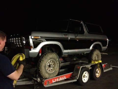 1979 Ford Bronco - A two-tone black and silver 1979 Ford Bronco is loaded onto a U-Haul trailer at night.