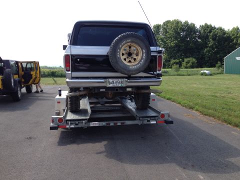 1979 Ford Bronco - A Ford Bronco is loaded onto a trailer, with a yellow Jeep visible to the left.