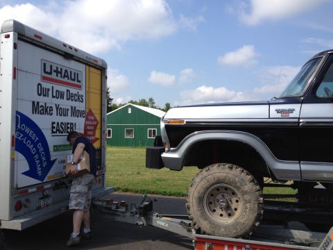1979 Ford Bronco - A man loads a box into a U-Haul truck next to a lifted Ford Bronco.