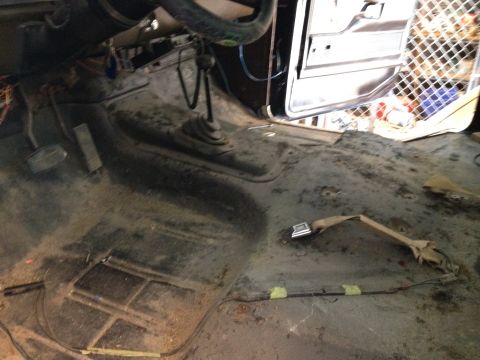 1979 Ford Bronco - The interior of a vehicle shows signs of wear and tear, with exposed wiring and a worn floor.