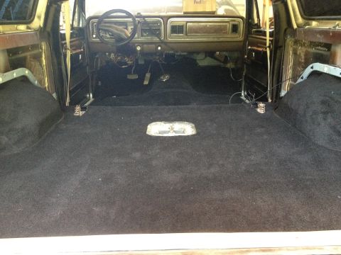 1979 Ford Bronco - The interior of a 1979 Ford Bronco shows new black carpeting and exposed wiring under the dashboard.