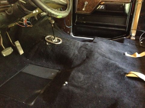 1979 Ford Bronco - The interior of a 1979 Ford Bronco, showing the floor, pedals, and steering wheel, with black carpeting installed.