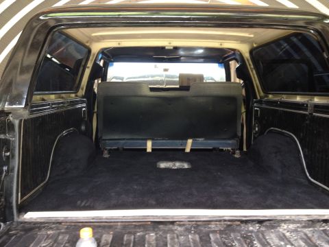 1979 Ford Bronco - The spacious interior cargo area of a 1979 Ford Bronco features black carpeting and a folded rear seat.