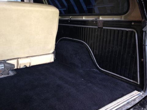 1979 Ford Bronco - The interior cargo space of the vehicle features dark carpeting and a beige seat.