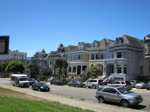 1991 Ford LTD Crown Victoria - A row of colorful Victorian houses lines a street in San Francisco, with various cars parked along the curb.