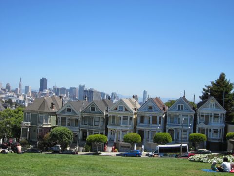 1991 Ford LTD Crown Victoria - A row of colorful Victorian houses stands against the San Francisco skyline under a clear blue sky.