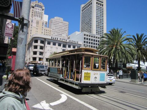 1991 Ford LTD Crown Victoria - A cable car travels down a street in San Francisco, with Saks Fifth Avenue visible in the background.