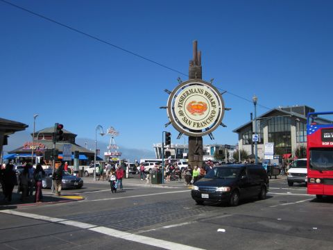 1991 Ford LTD Crown Victoria - A busy street scene at Fisherman's Wharf in San Francisco, with a prominent sign and various vehicles.