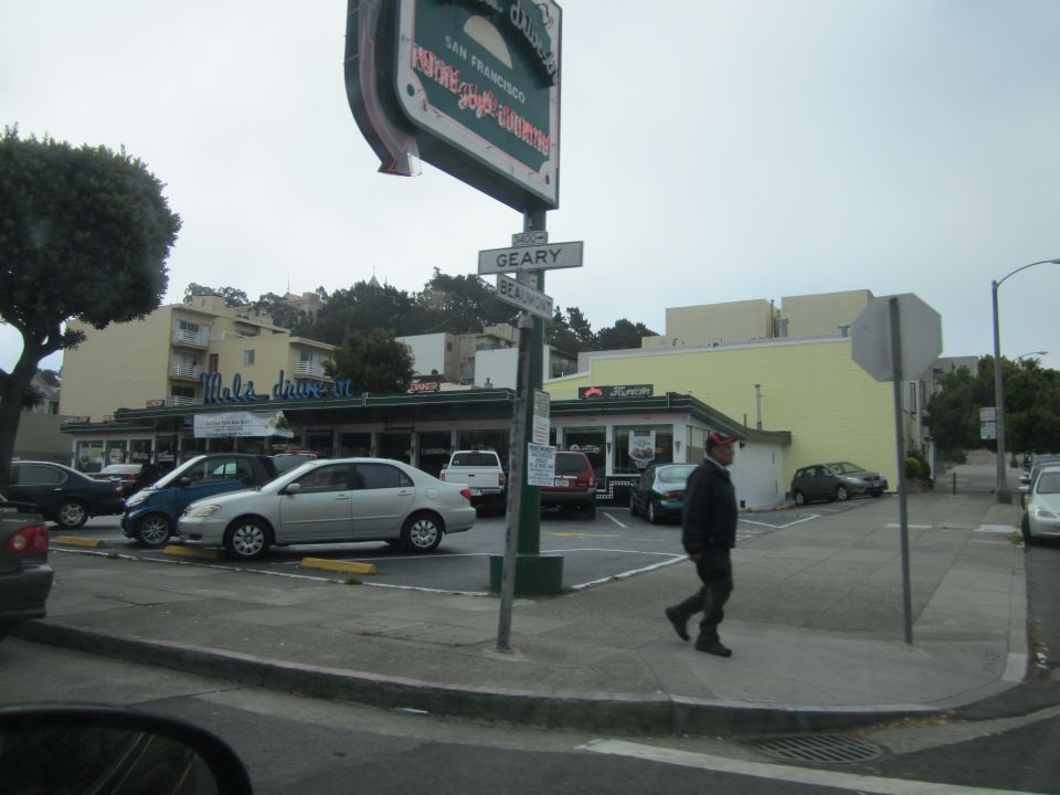 Silver sedan and blue sedan parked in front of a diner with a large sign