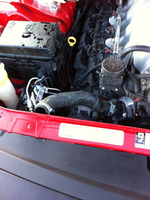 2010 Dodge Challenger - Close-up view of an engine bay, showing hoses, electrical components, and a red structural rail.