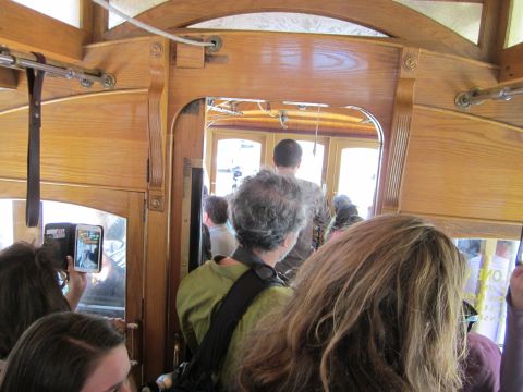 1991 Ford LTD Crown Victoria - View from inside a vintage wooden tram as passengers prepare to board through the rear doors.