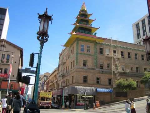 1991 Ford LTD Crown Victoria - A yellow tour bus drives down California Street in San Francisco, passing by a building with a pagoda-style roof.