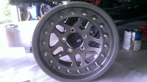 1978 Ford Bronco - A single gray alloy wheel is shown, with a can of paint nearby.