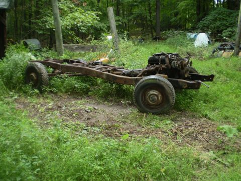 1979 Ford Bronco - A rusted vehicle frame with its engine and wheels sits in overgrown grass, with a Supermotors.net logo in the corner.