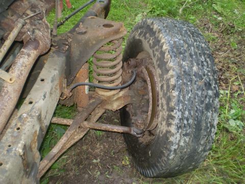 1979 Ford Bronco - Close-up of a heavily rusted vehicle chassis and suspension system, including a tire and wheel assembly.