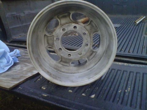 1994 Ford Bronco - An aluminum wheel with a silver finish and eight lug holes is shown resting in the bed of a truck.