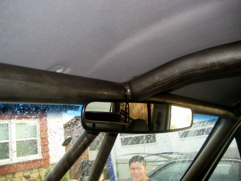 1996 Ford Bronco - The interior of a vehicle is visible, a prominent roll cage and a rearview mirror.