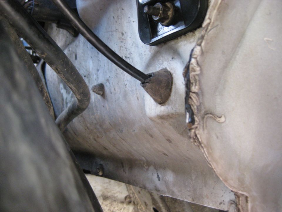 Close-up of a rubber grommet and wiring harness on a vehicle's undercarriage