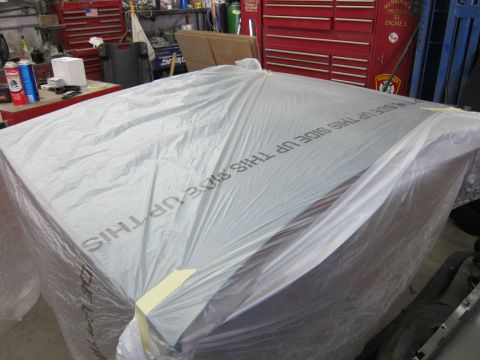 1991 Ford LTD Crown Victoria - A vehicle is covered in plastic sheeting, obscuring its details, in what appears to be a workshop or garage.