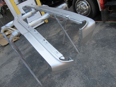 1991 Ford LTD Crown Victoria - A car bumper is prepped for painting, supported by sawhorses.