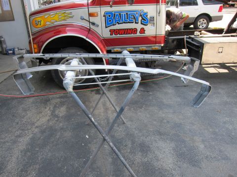 1991 Ford LTD Crown Victoria - A car bumper is prepped for painting, with a tow truck and another vehicle in the background.