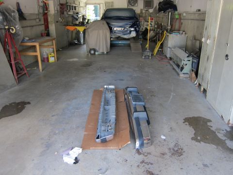 1991 Ford LTD Crown Victoria - Car parts laid out on the floor of a workshop, with a vehicle on a lift in the background.
