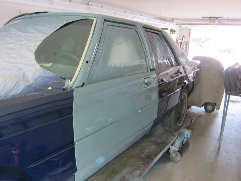 1991 Ford LTD Crown Victoria - A car is being prepped for a new paint job in a garage, with different sections masked and primed.